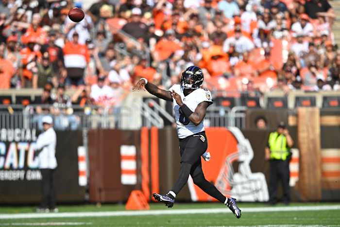 Lamar Jackson throws the ball with a crowd of Browns fans in the stadium seats behind him